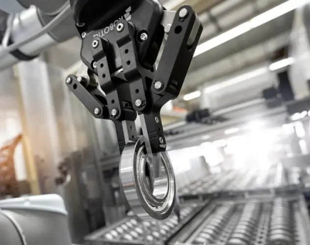 A robotic arm precisely holding a metal bearing in a high-tech industrial setting, representing automation, precision engineering, and modern manufacturing processes.